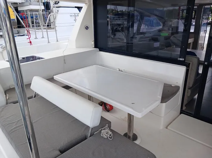 Bendigo Yacht Photos Pics Outdoor seating area on a 2021 Leopard 40 catamaran with a white table and cushioned benches.