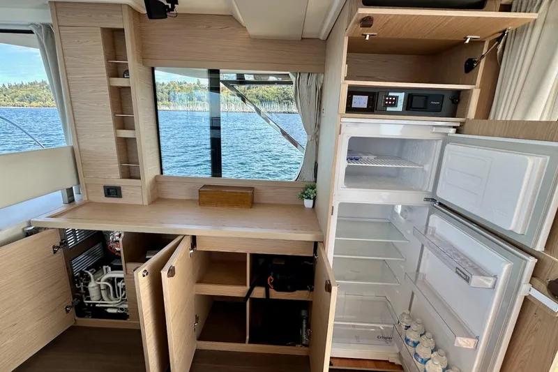 Fret Knot Yacht Photos Pics Interior of 2024 Beneteau Swift Trawler 41 Sedan with open cabinets and refrigerator.