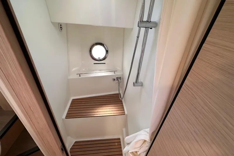 Fret Knot Yacht Photos Pics Shower area in 2024 Beneteau Swift Trawler 41 Sedan with wooden flooring and porthole.
