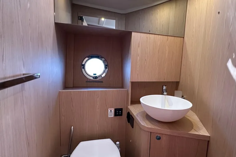 Fret Knot Yacht Photos Pics 2024 Beneteau Swift Trawler 41 Sedan bathroom with modern sink and porthole window.