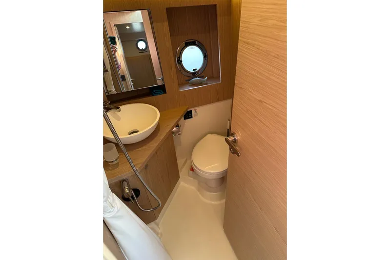 Fret Knot Yacht Photos Pics 2024 Beneteau Swift Trawler 41 Sedan bathroom with modern fixtures and porthole window.