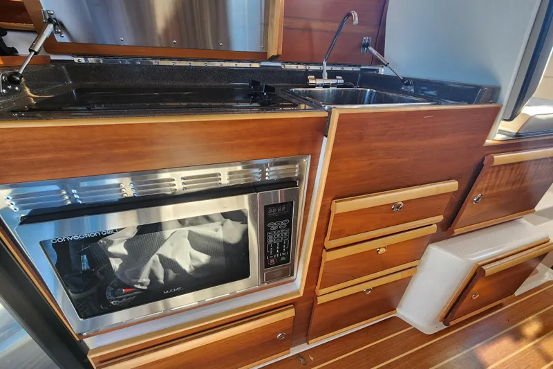  Yacht Photos Pics 2021 Cutwater C-32 CB galley with microwave, sink, and wooden cabinetry.