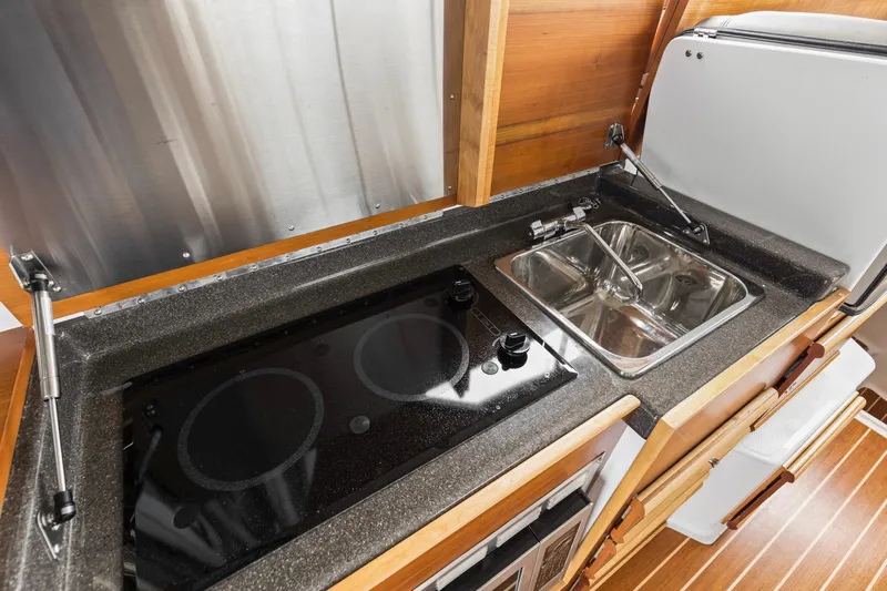  Yacht Photos Pics 2021 Cutwater C-32 CB kitchen with stove, sink, and wooden cabinetry.