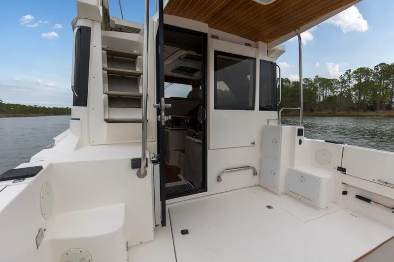  Yacht Photos Pics 2021 Cutwater C-32 CB boat deck with open cabin door, near serene water and trees.