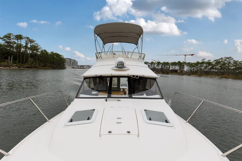  Yacht Photos Pics 2021 Cutwater C-32 CB boat cruising on a scenic river with trees and buildings.