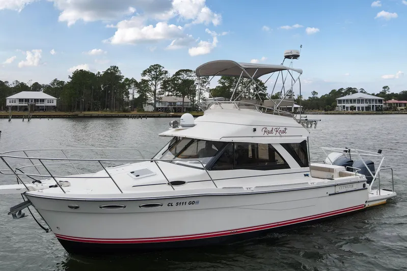  Yacht Photos Pics 2021 Cutwater C-32 CB boat on a serene lake with houses in the background.