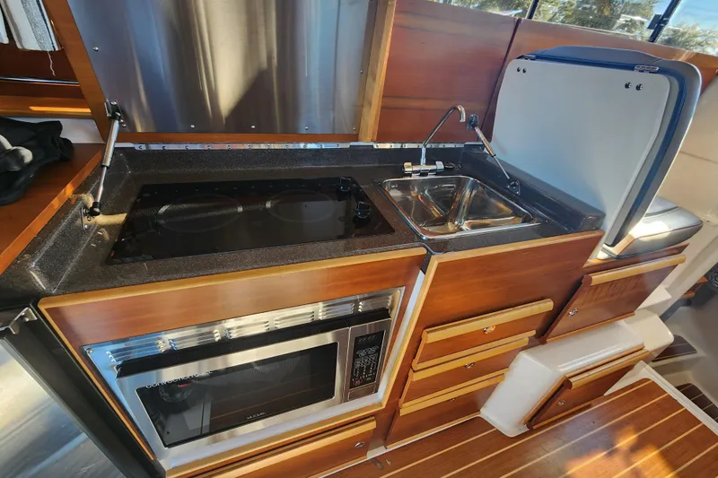  Yacht Photos Pics 2021 Cutwater C-32 CB galley with stove, sink, and microwave in a compact layout.