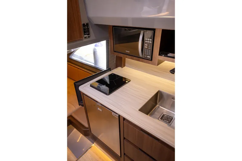  Yacht Photos Pics Modern kitchen interior in 2026 Hanover 447 RV with microwave, sink, and induction cooktop.