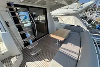 Outdoor seating area on a 2020 Prestige 420 yacht with wooden table and stairs.