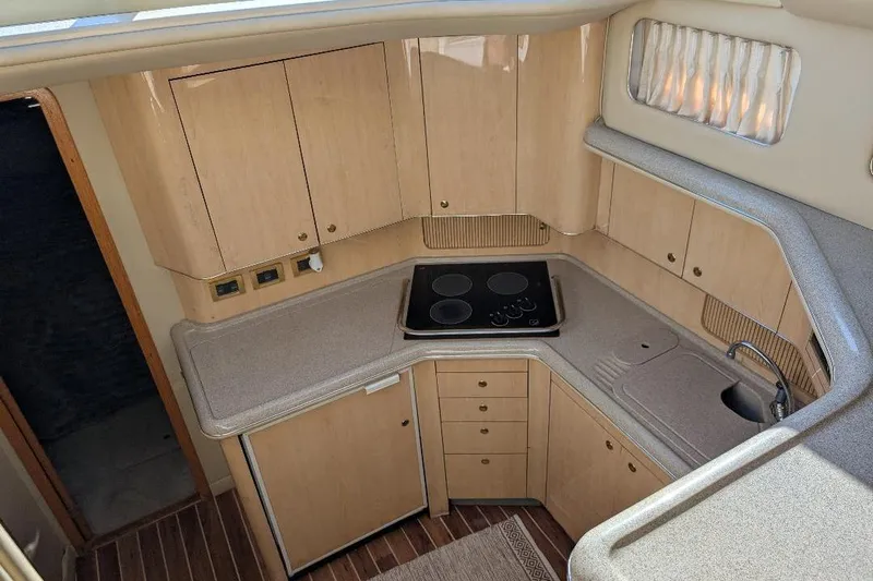 Smitten Yacht Photos Pics 2000 Sea Ray 420 Aft Cabin yacht kitchen with stove, sink, and wooden cabinetry.