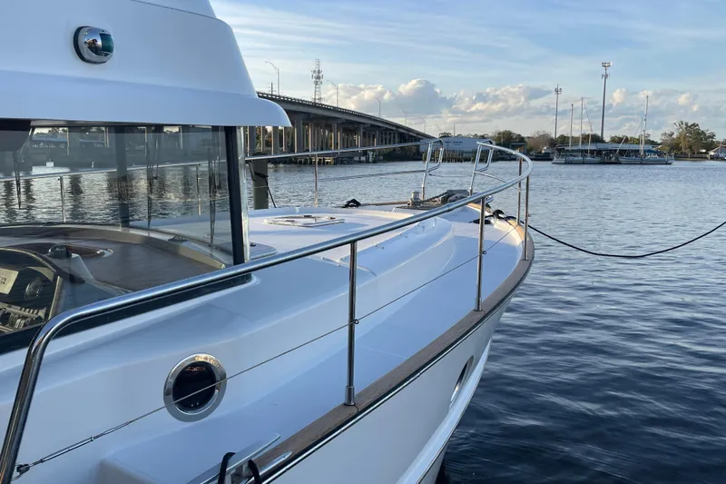 Miss Adventure Yacht Photos Pics 2013 Beneteau Swift Trawler 44 docked by a scenic waterfront with a bridge view.