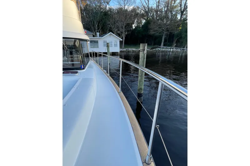 Miss Adventure Yacht Photos Pics 2013 Beneteau Swift Trawler 44 docked by a serene waterfront house.