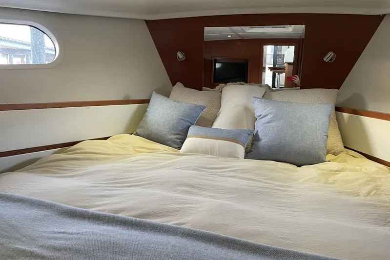 Miss Adventure Yacht Photos Pics Cozy bedroom interior of 2013 Beneteau Swift Trawler 44 with plush pillows and soft lighting.