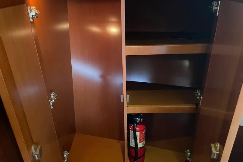 Miss Adventure Yacht Photos Pics Open wooden cabinet with shelves and a fire extinguisher on a 2013 Beneteau Swift Trawler 44.