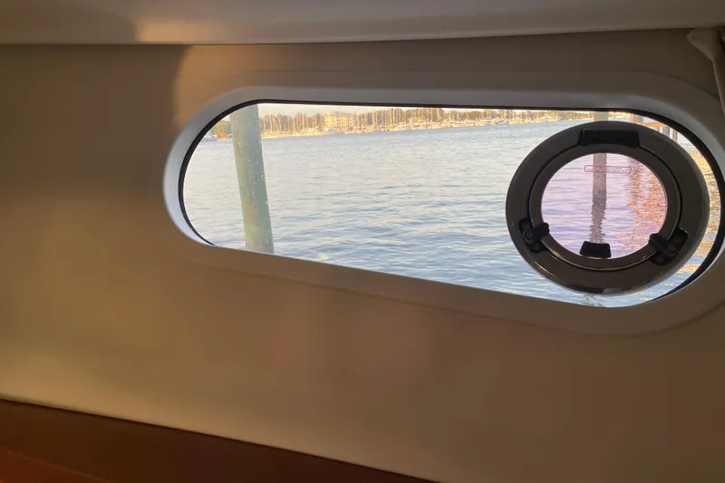 Miss Adventure Yacht Photos Pics Porthole view from 2013 Beneteau Swift Trawler 44, overlooking calm waters and distant shoreline.