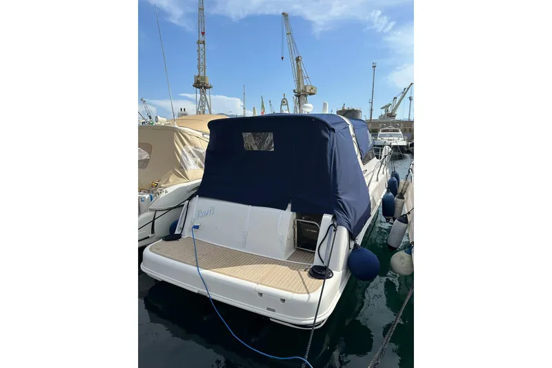 Piccopi Yacht Photos Pics 2007 Mano Marine 32.50 Sport boat docked, covered with blue canopy, in marina.