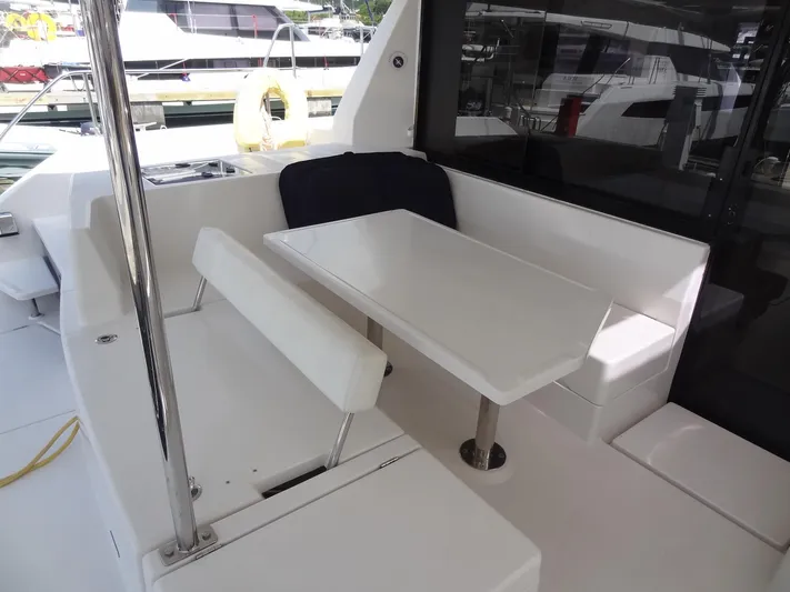 Maupiti Yacht Photos Pics Outdoor seating area on a 2019 Leopard 40 catamaran, featuring a white table and cushioned benches.