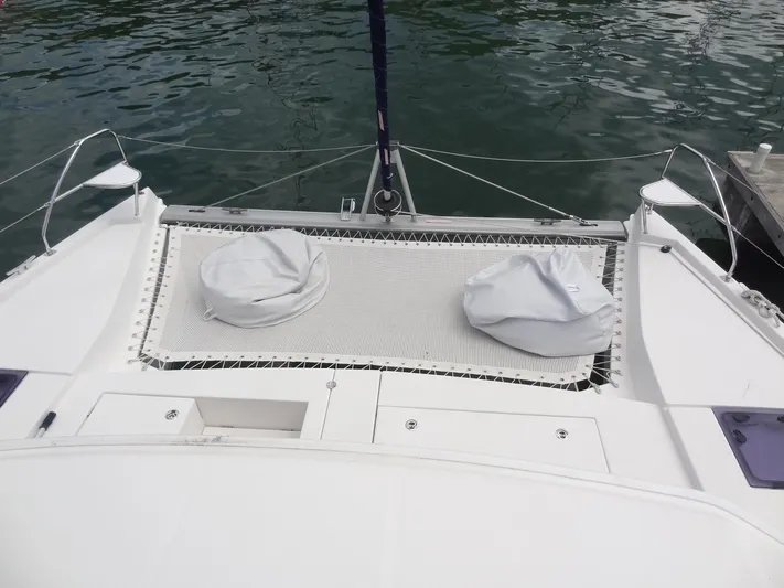 Maupiti Yacht Photos Pics 2019 Leopard 40 catamaran with netted deck and covered cushions, docked on calm water.