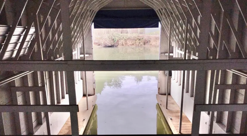  Yacht Photos Pics Interior view of a custom boathouse, 2013, with water reflection and wooden structure.