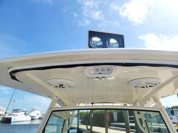  Yacht Photos Pics 2018 Scout 275 LXF boat roof with speakers and lights, docked under a clear blue sky.