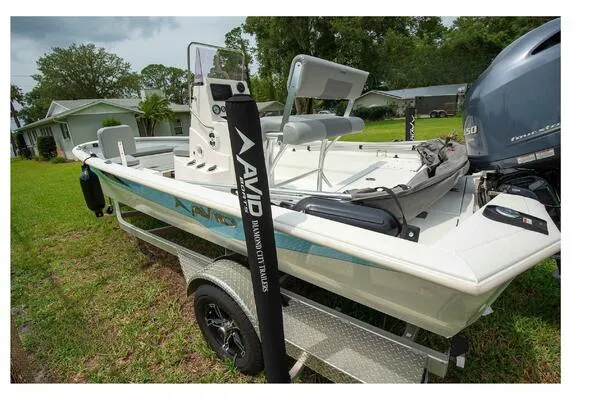 Avid 21 Fusion 2022 boat on trailer, parked on grass, with Yamaha outboard motor.