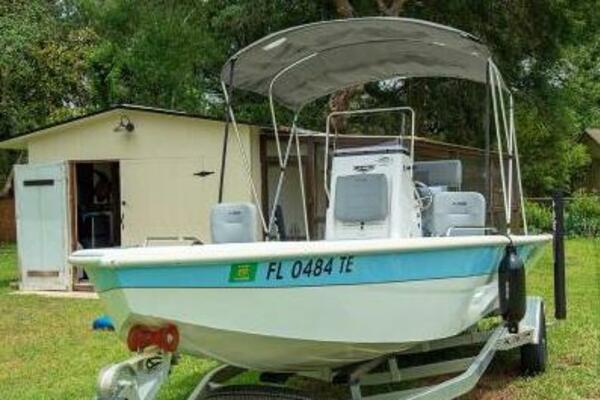 2022 Avid 21 Fusion boat on trailer, parked in grassy yard near a shed.