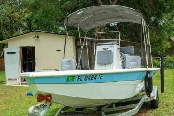 2022 Avid 21 Fusion boat on trailer, parked in grassy yard near a shed.