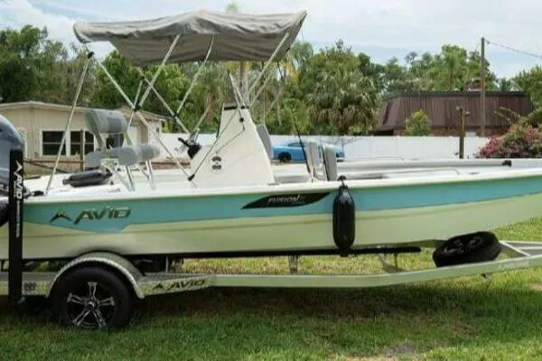 Avid 21 Fusion 2022 boat on trailer with canopy, parked on grass.