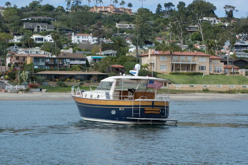 True Grit Yacht Photos Pics 2003 Apreamare 40 yacht cruising near coastal homes with American flag.