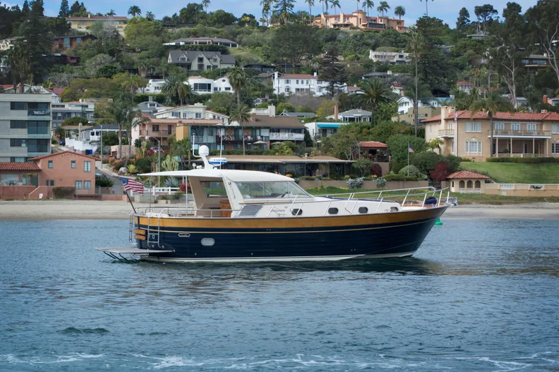 True Grit Yacht Photos Pics 2003 Apreamare 40 yacht cruising near coastal homes with lush greenery.