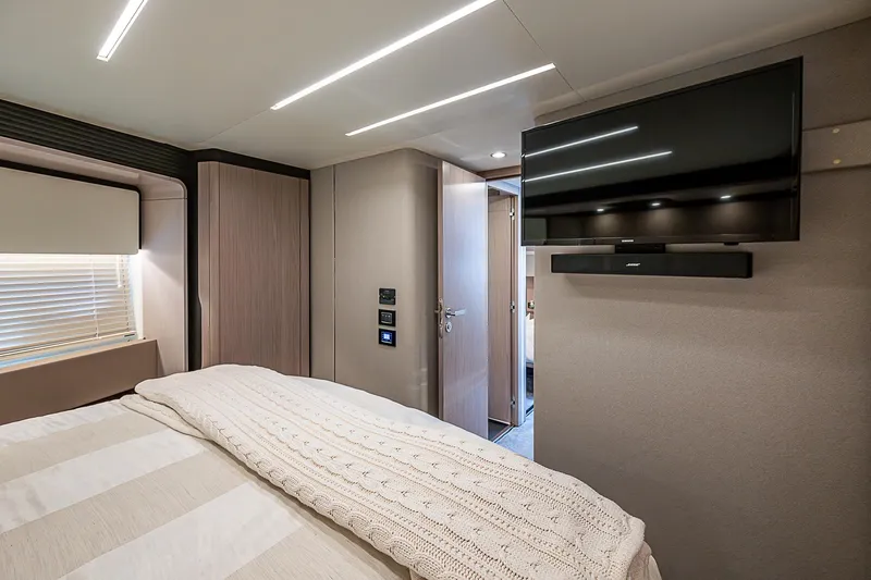 Liquid Asset Yacht Photos Pics Luxurious bedroom interior of 2020 Azimut 66 yacht with modern TV and cozy bedding.
