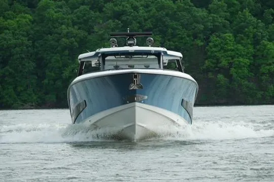 Fast Money Yacht Photos Pics 2021 Boston Whaler 420 Outrage cruising on a lake with lush green forest backdrop.