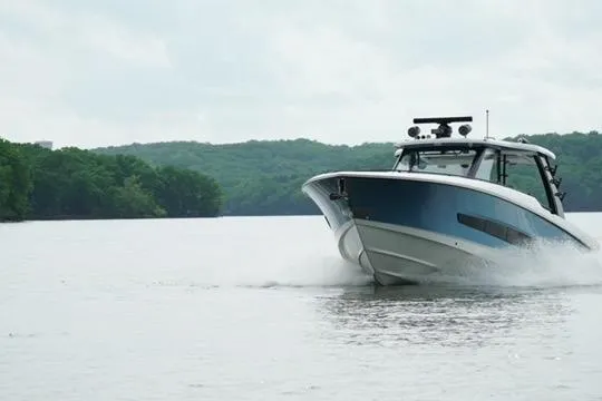Fast Money Yacht Photos Pics 2021 Boston Whaler 420 Outrage cruising on a serene lake with lush green backdrop.