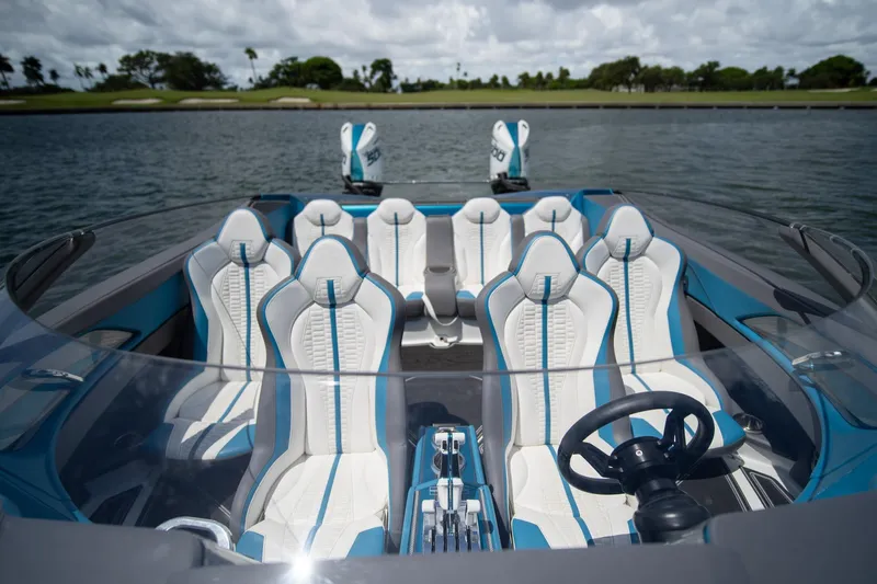  Yacht Photos Pics 2024 MTI 440X boat interior with sleek white and blue seating, steering wheel, and water backdrop.