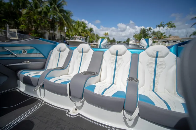  Yacht Photos Pics Luxurious seating in 2024 MTI 440X boat, featuring white and blue upholstery with palm trees in background.