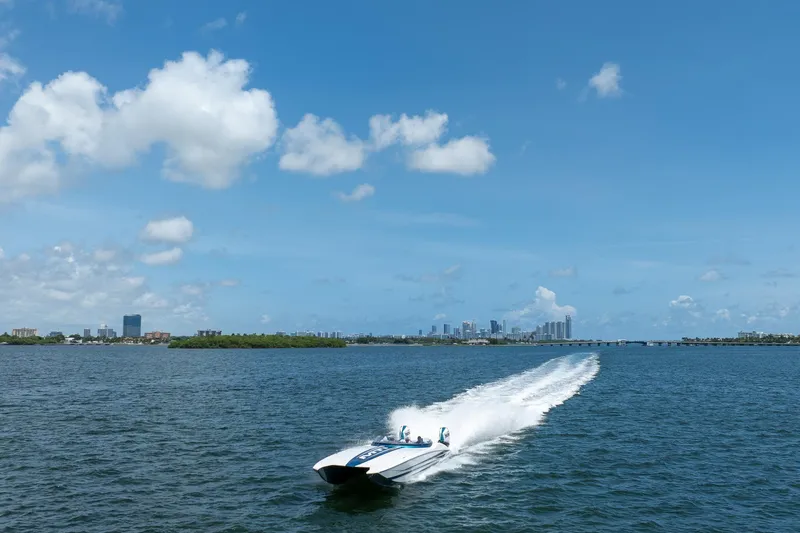  Yacht Photos Pics 2024 MTI 440X speedboat cruising on open water with city skyline in background.