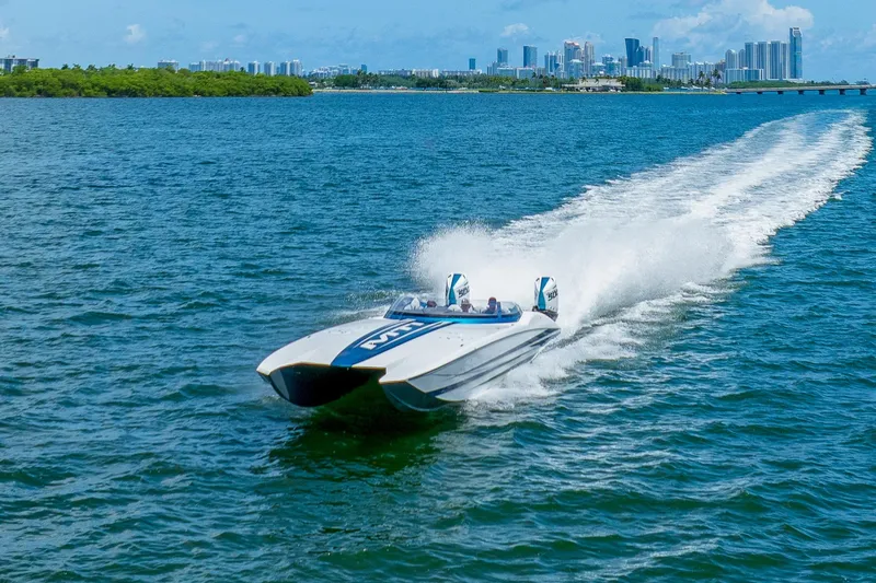  Yacht Photos Pics 2024 MTI 440X powerboat speeding on blue water with city skyline in background.