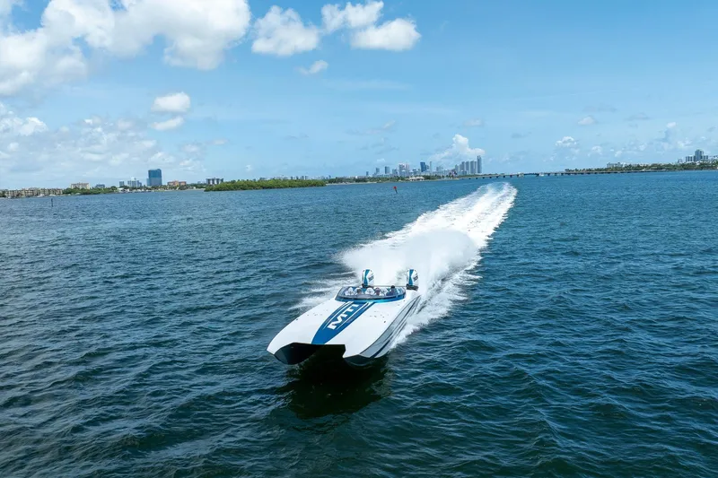  Yacht Photos Pics 2024 MTI 440X speedboat cruising on open water with city skyline in background.