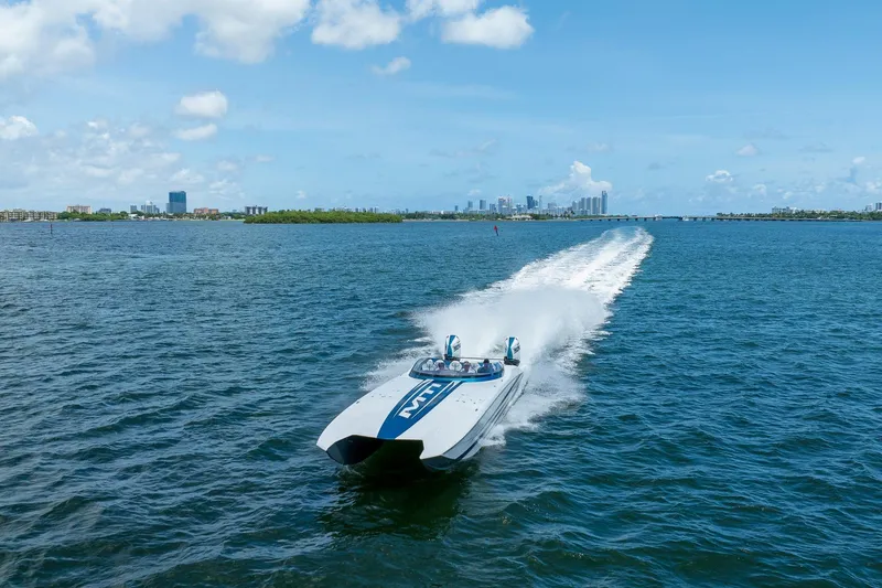  Yacht Photos Pics 2024 MTI 440X speedboat cruising on open water with city skyline in background.