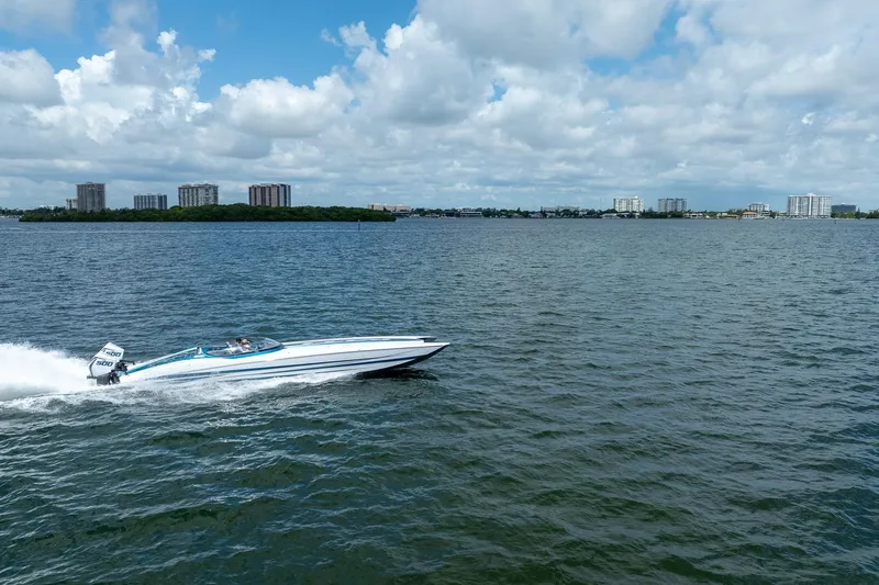 Yacht Photos Pics 2024 MTI 440X speedboat cruising on a vast, scenic waterway under a partly cloudy sky.