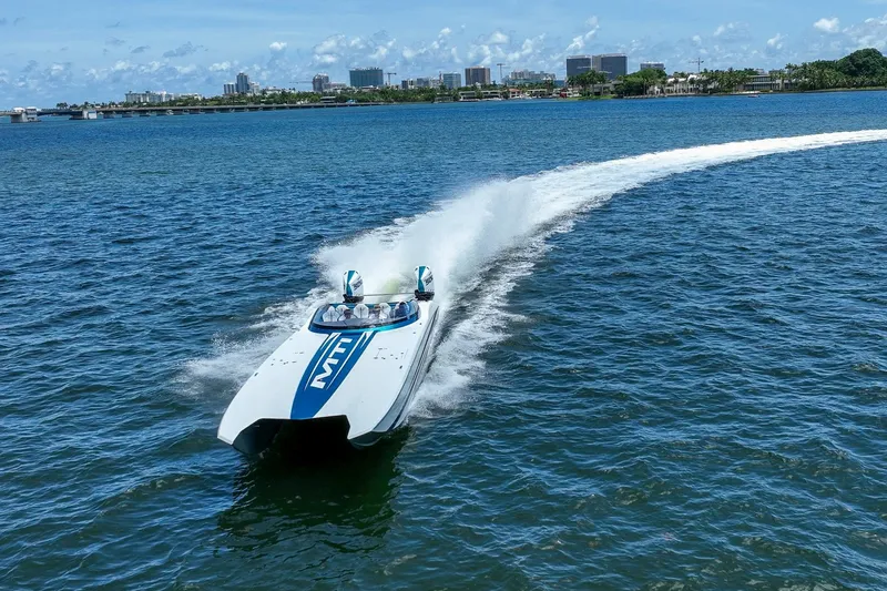  Yacht Photos Pics 2024 MTI 440X speedboat cruising on blue water near city skyline.