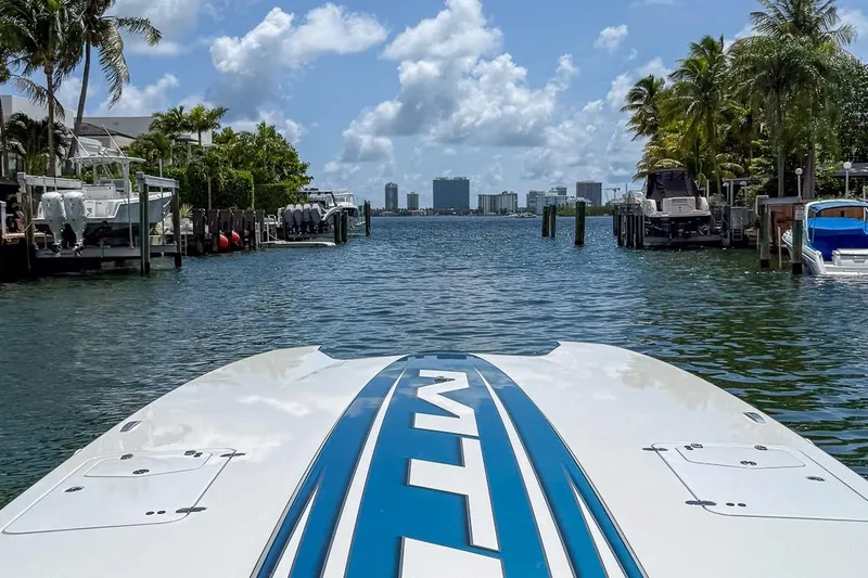  Yacht Photos Pics 2024 MTI 440X boat cruising through a scenic waterway with palm trees and city skyline.