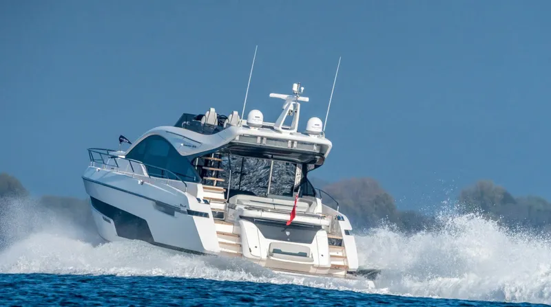  Yacht Photos Pics 2026 Fairline Phantom 65 yacht cruising on open water, creating waves.