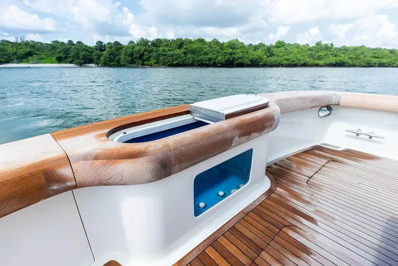 Typhoon I Yacht Photos Pics 2008 Tribute Sportfish boat deck with wooden finish, featuring a livewell, against a scenic water backdrop.