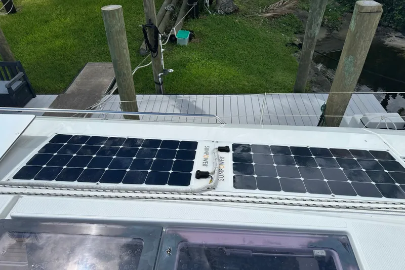 Big Enough Yacht Photos Pics Solar panels on 2014 Fountaine Pajot Helia 44 catamaran, docked near lush greenery.