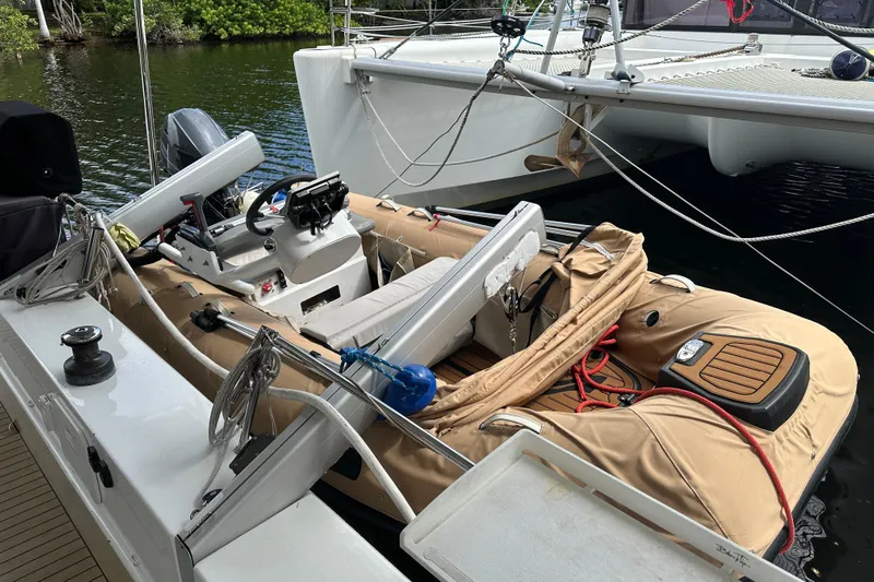 Big Enough Yacht Photos Pics 2014 Fountaine Pajot Helia 44 catamaran with inflatable dinghy, docked in a serene waterway.