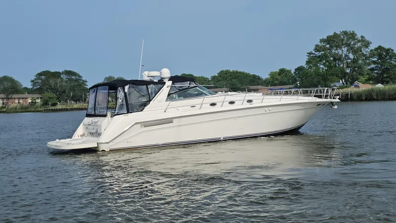  Yacht Photos Pics 1999 Sea Ray 500 Sundancer yacht cruising on a calm river with trees in the background.