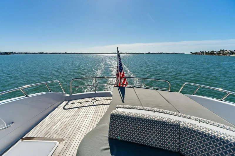 Summerwind Yacht Photos Pics Luxurious 2005 Lazarra 80 yacht deck with American flag, overlooking serene ocean waters.