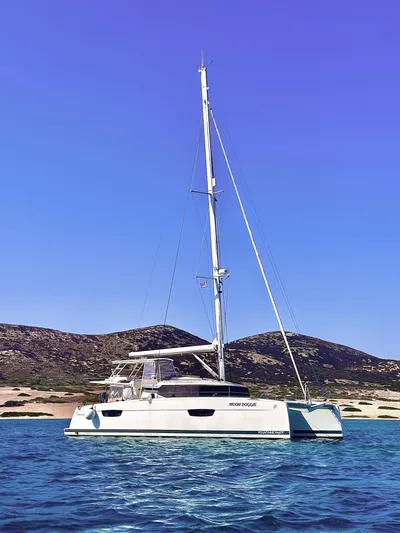 Moon Doggie Yacht Photos Pics 2022 Fountaine Pajot Tanna 47 catamaran sailing near scenic coastline.