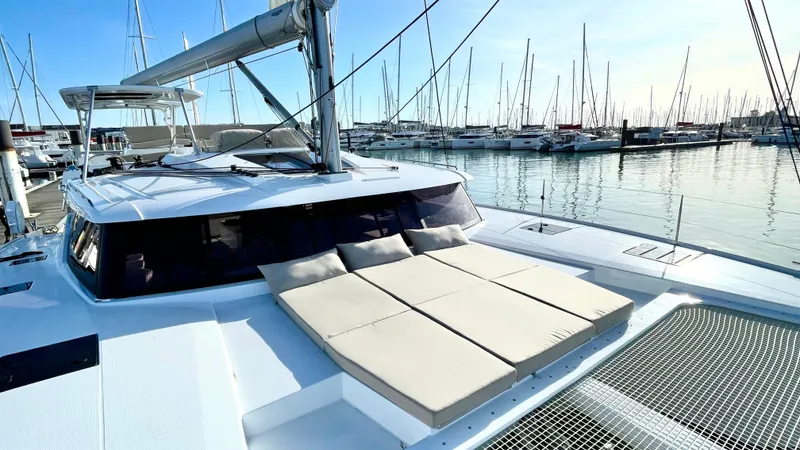 Moon Doggie Yacht Photos Pics 2022 Fountaine Pajot Tanna 47 catamaran docked in marina, featuring spacious deck and sunbathing area.